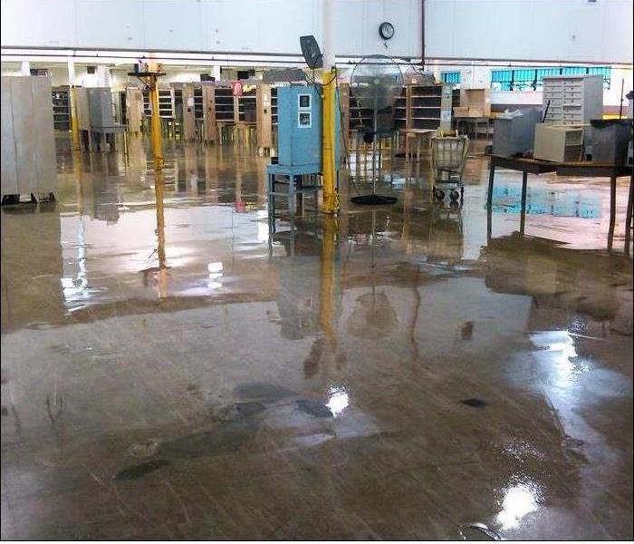warehouse concrete floor covered with water showing metal equipment and support poles